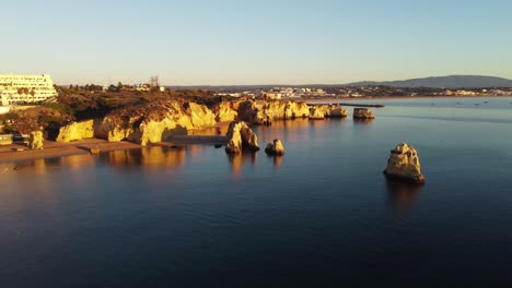 aerial view, 4k drone shots, praia dona ana with cliffs, lagos at sunrise in autumn, in the algarve, portugal