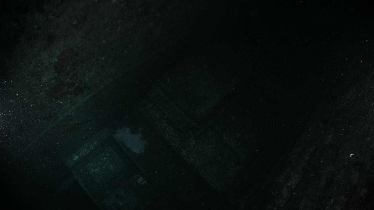 Unique underwater scuba divers view penetrating through a hatch of a sunken shipwreck to reveal a dark chamber of the recently scuttled Navy ship the Ex-HMAS Tobruk