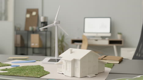 miniatura de turbina eólica y modelo de casa en la mesa de oficina 2