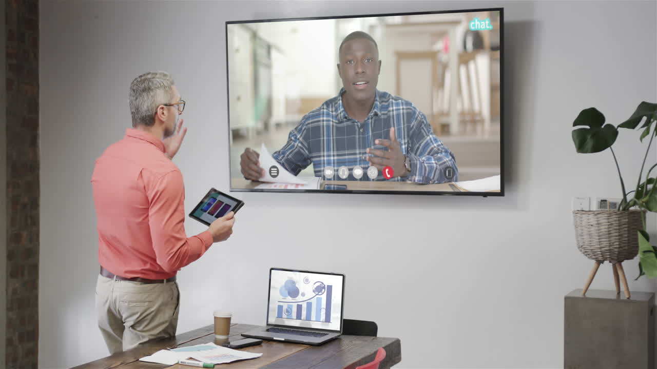 Caucasian businessman on video call with african american male colleague on tv screen