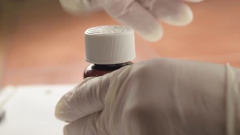 opening bottle of medication with hygiene gloves close up shot