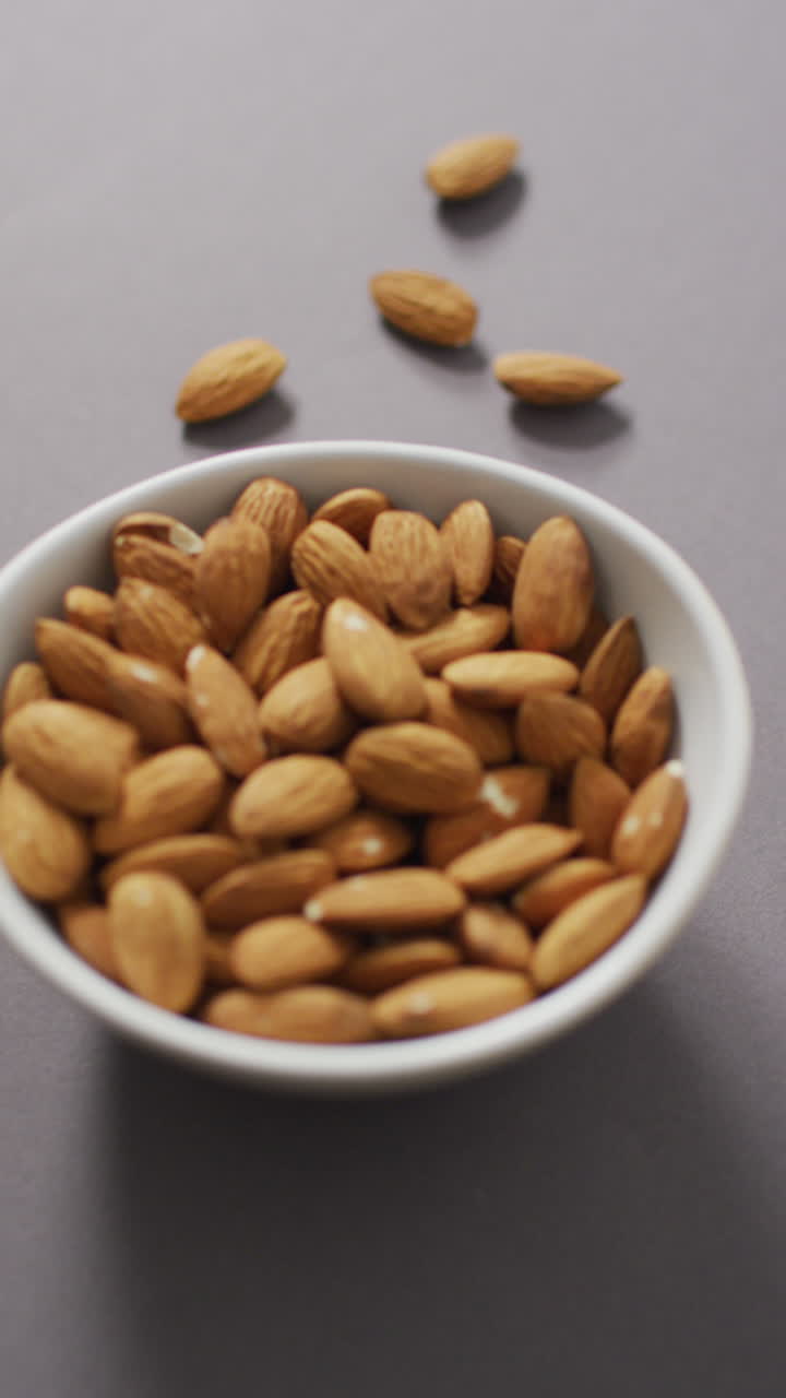 video vertical de un cuenco de almendras en un fondo lila