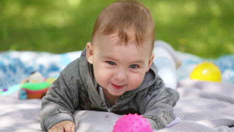 cheerful active caucasian baby boy clapping hands on the floor. cute lovely child resting in the nature. close up.