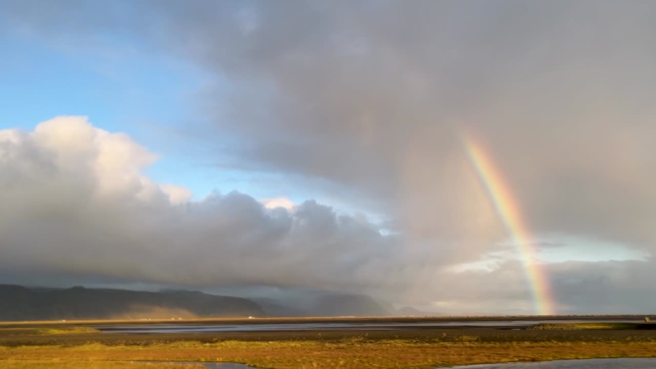 el paisaje mágico de islandia con nubes lluviosas y arco iris, vista desde un coche en movimiento