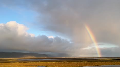 magical landscape of iceland with rainy clouds and rainbow, view from moving car