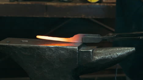 Slow-motion-close-up-of-blacksmith-forge-hammering-on-hot-glowing-metal-in-a-workshop