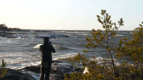 man from behind photographing rough sea