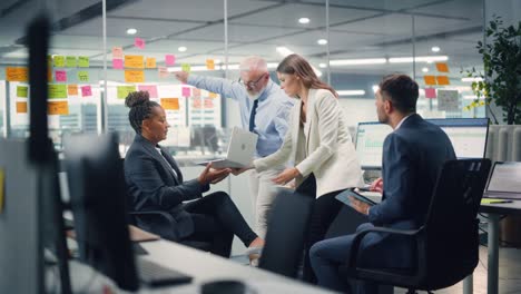 in modern office: diverse team of managers use laptop and tablet computers at a company meeting discussing business projects. young, motivated and experienced employees brainstorm in conference room.
