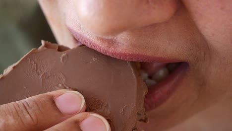 close-up of a woman taking a bite of chocolate