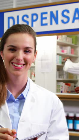 pharmacist writing on notepad in pharmacy