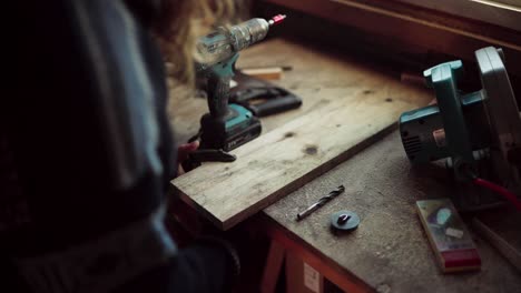 the man clamps the wooden plank securely and drills the edge for the diy hot tub - close up