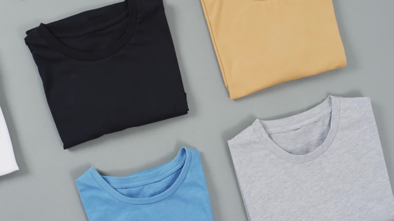 Video of flat lay of t shirts with copy space on grey background