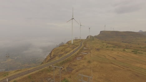 Ein-Elektrisches-Motorrad,-Das-Vor-Der-Kulisse-Von-Windmühlen-Fährt,-Die-Grüne,-Erneuerbare-Energie-Erzeugen