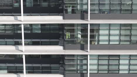 Ascending-drone-shot-of-skyscraper's-windows-with-balconies