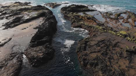 slow tilt reveals the relaxing flow of the tide pools on the shore of porto das salemas