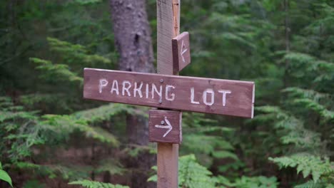 a parking lot sign along a path in the woods