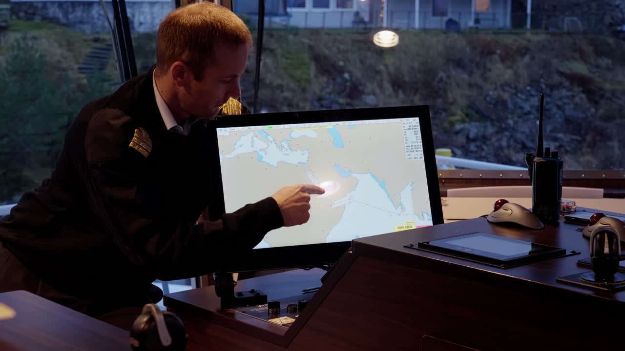 el capitán del barco traza una ruta a través del océano índico, el mar rojo, el canal de suez, sacude la cabeza.