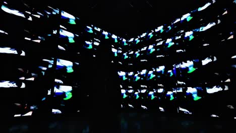 A person silhouetted against a wall of colorful video screens