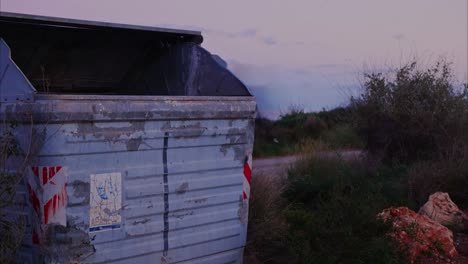 Un-Contenedor-De-Basura-Y-Basura-Al-Costado-De-La-Carretera-Con-Autos-Que-Pasan-A-Toda-Velocidad-Al-Atardecer---Lapso-De-Tiempo-Estático