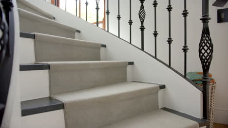 Carpeted-spiral-staircase-with-metal-balustrades-in-hallway-of-luxury-home,-copy-space,-slow-motion