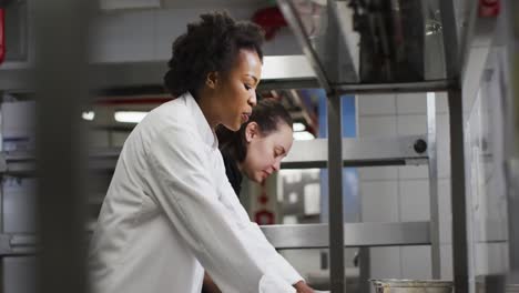 dos cocineras diversas preparando masa y hablando en la cocina del restaurante