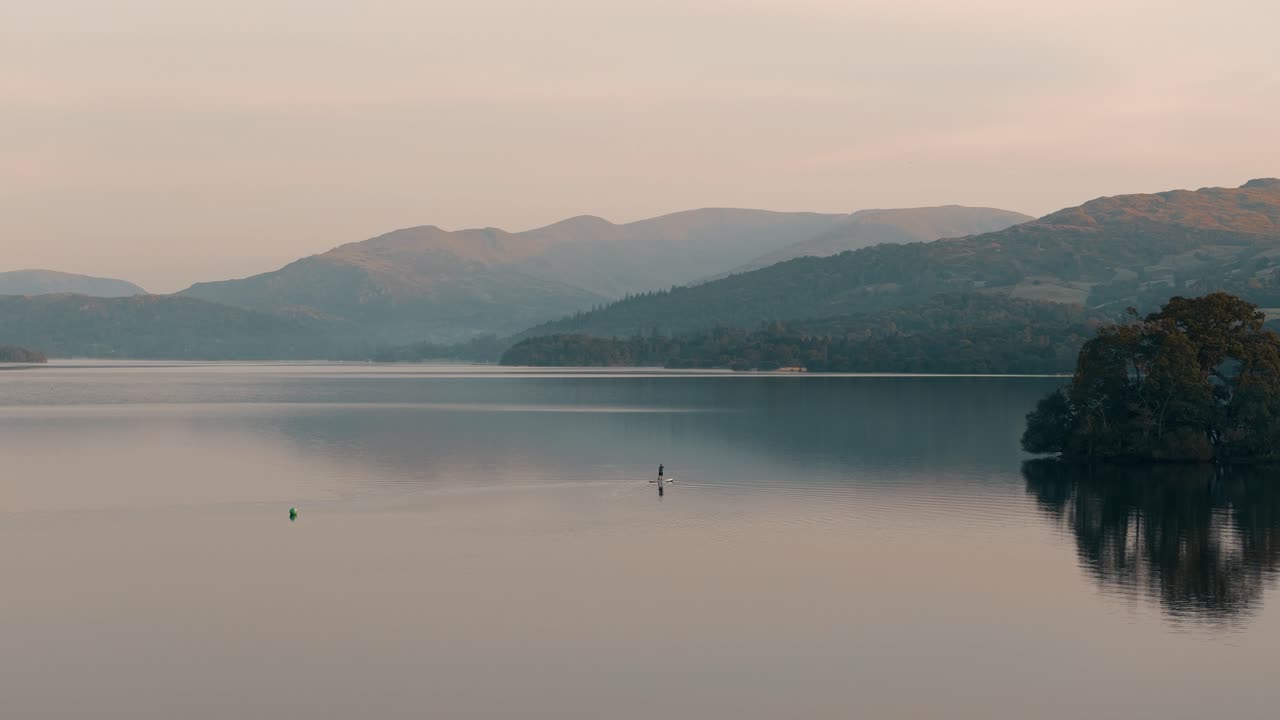 Peaceful Paddleboarding at Sunset on a Calm Lake Surrounded by Mountains