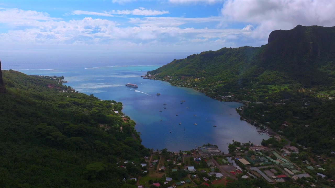 Moorea, Fransız Polinezyası'nda Cooks Opunohu Koyu plaj evleri, dramatik volkanik yüksek sivri zirveler ve engebeli arazi. Belvedere Gözetleme Noktası'ndan güneşli sabah, mavi gökyüzü ve bulutlarla ileriye doğru drone hava çekimi.