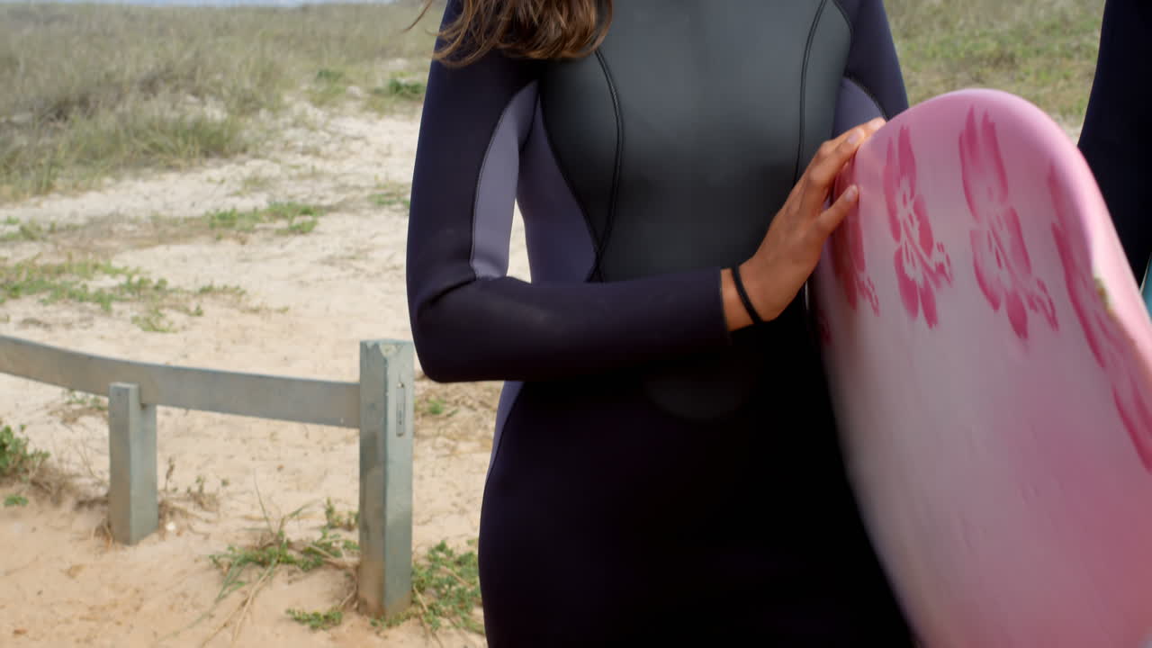Surffaajapariskunta seisoo surffilaudan kanssa 4k