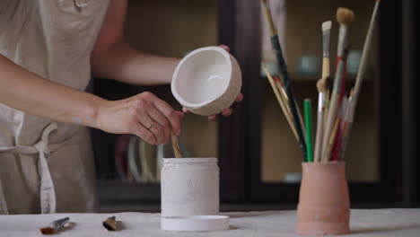 mujer pintando un cuenco de cerámica en un estudio de arte