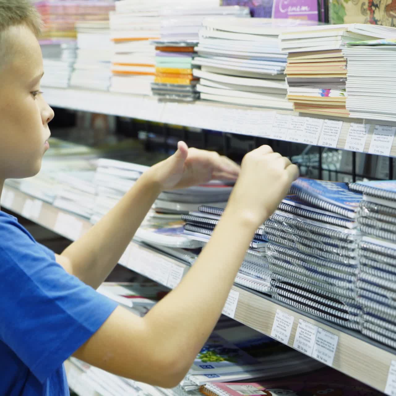 Vinnitsa, Ukraine - August, 2018: Boy chooses office supplies. Many colorful tools and supplies on the shelf of a stationery shop