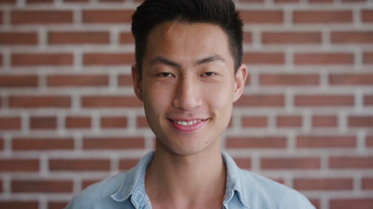 ritratto indipendente giovane uomo asiatico studente sorridente che gode del successo che sembra felice sicuro di sé maschio in slow motion