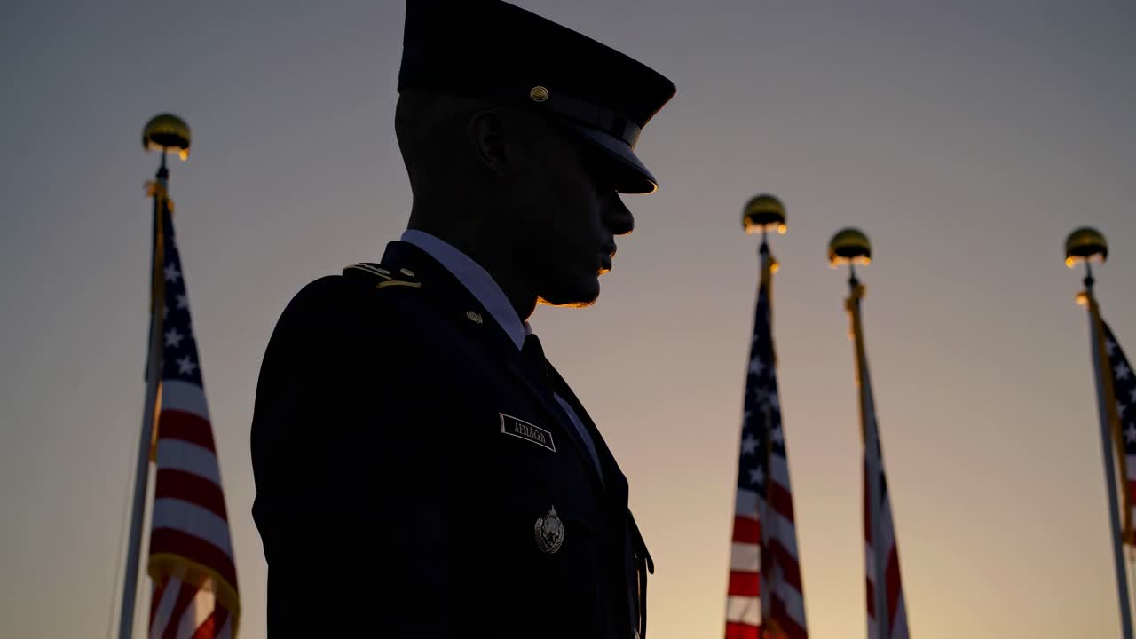 Silhouette di un soldato in uniforme con cielo al tramonto e bandiere sullo sfondo