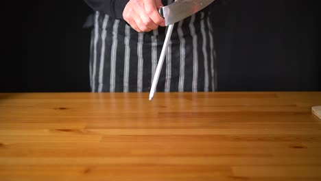 Slow-motion-of-a-man-Chef-using-various-techniques-to-sharpen-a-knife-with-his-hands,-using-a-professional-knife-and-a-diamond-sharpening-steel