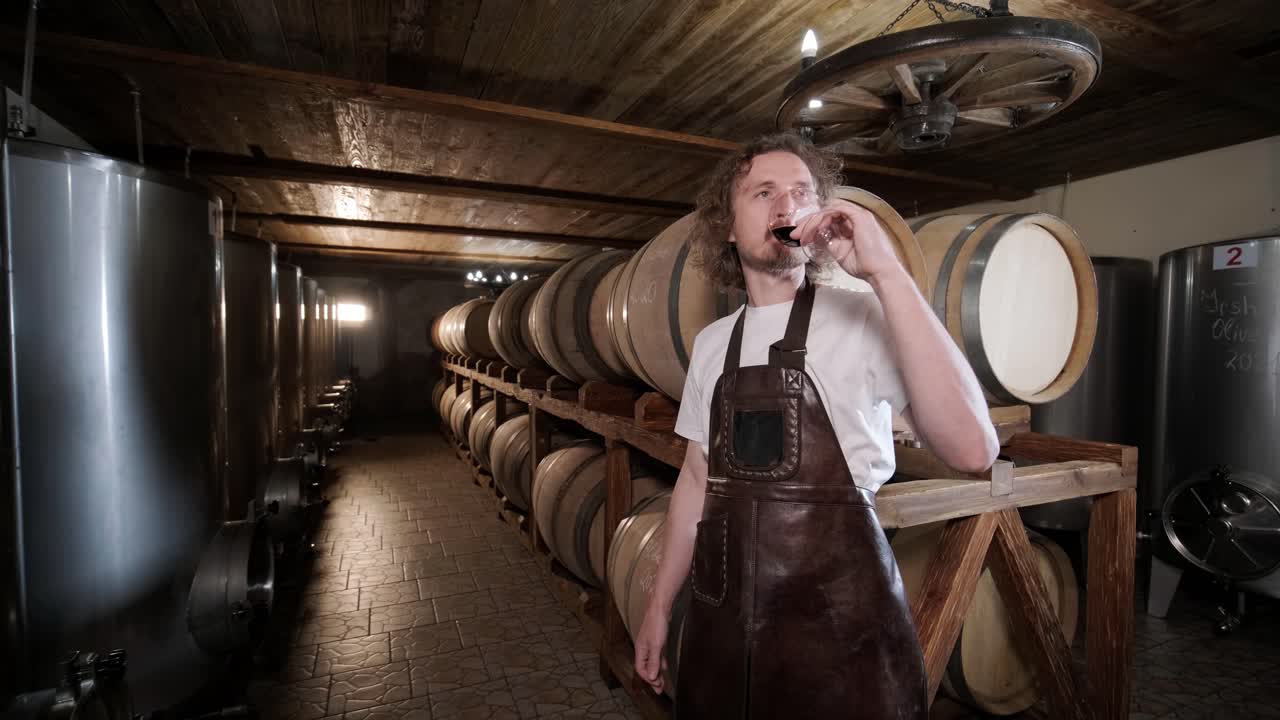 la toma auténtica de un sommelier masculino exitoso es degustar un sabor y comprobar la calidad del vino blanco vertido en vidrio transparente en una bodega de vino.