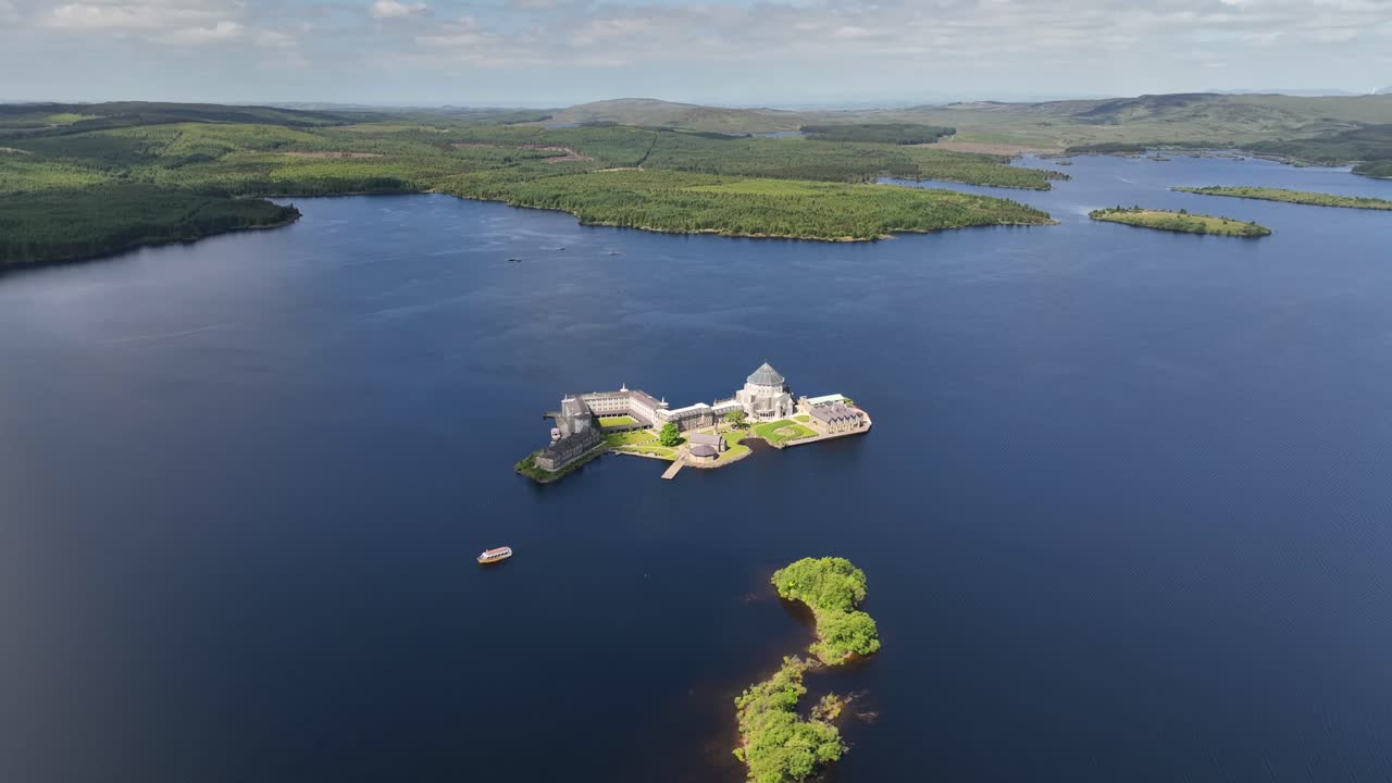 Lough Derg, County Donegal, Ireland, June 2023. Drone orbits clockwise around St. Patrick's Purgatory on Station Island with sunlight illuminating the grounds and lake water.