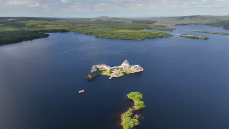lough derg, county donegal, ireland, june 2023. drone orbits clockwise around st. patrick's purgatory on station island with sunlight illuminating the grounds and lake water.