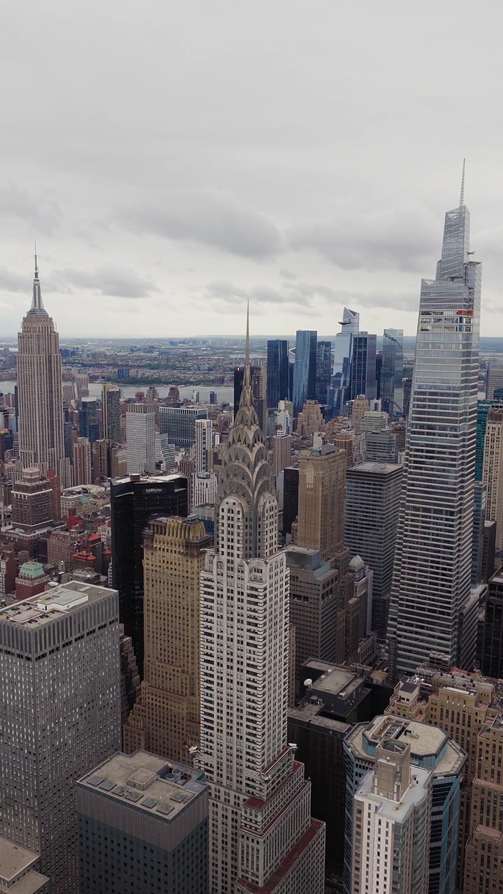 Inquadratura drone panoramica verticale lenta di Manhattan, New York. Chrysler Building in primo piano, Empire State Building sullo sfondo. Cielo nuvoloso e coperto. Filmato aereo cinematografico.
