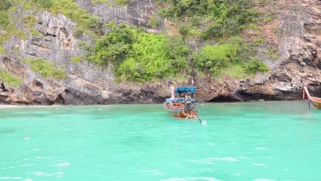 longtail boat in a turquoise bay with cliffs