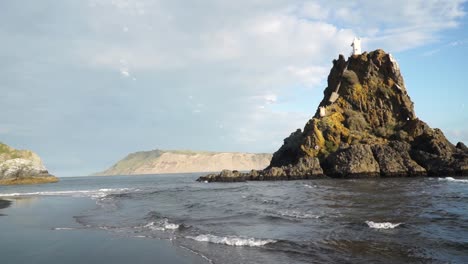 SLOWMO---Lighthouse-on-rock-Whatipu-Beach,-New-Zealand