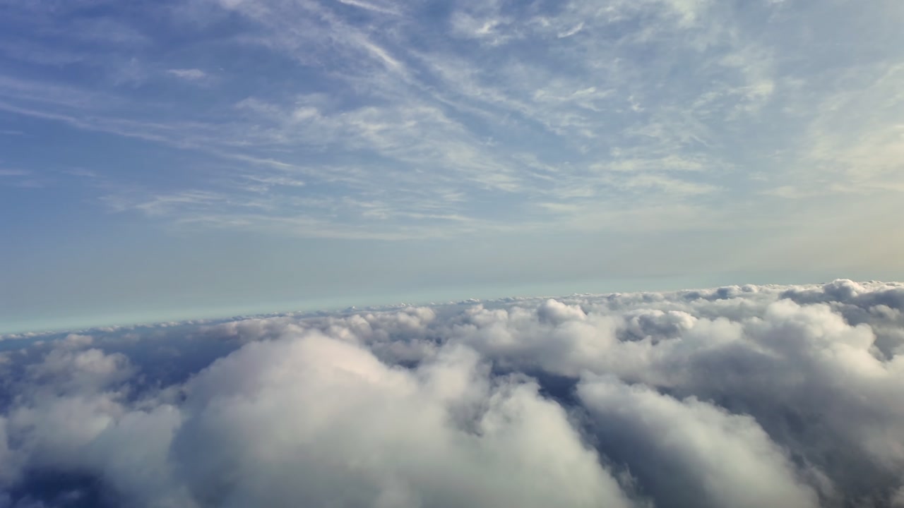 Pilot’s eye FPV view taken from a jet cockpit while flying at dawn over a layer of scattered cottony clouds in a right turn.