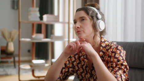 woman with serious facial expression wearing headphones in living room