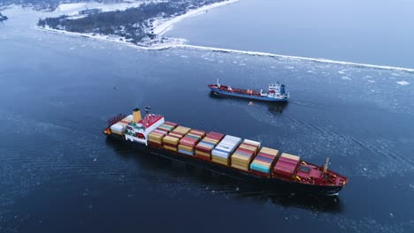 aerial shot of the cargo ship moving through the sea. in the background winter landscape.