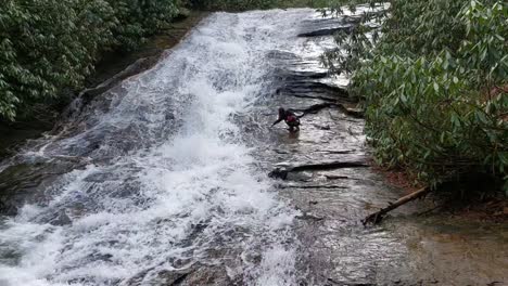 mujer sacando agua de una cascada