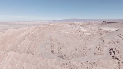 sideways drone shot flying over the dry sand desert mountains in san pedro de atacama chile south america on a blue sky day near mars valley and valley de la luna log