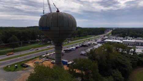 an aerial view of people on blue scaffolding, connected to a water tower as they are welding the old structure