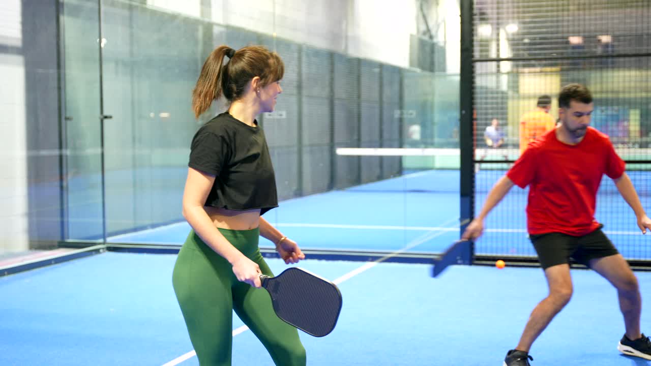 Mann und Frau spielen Padel-Tennis auf einem Hallenplatz