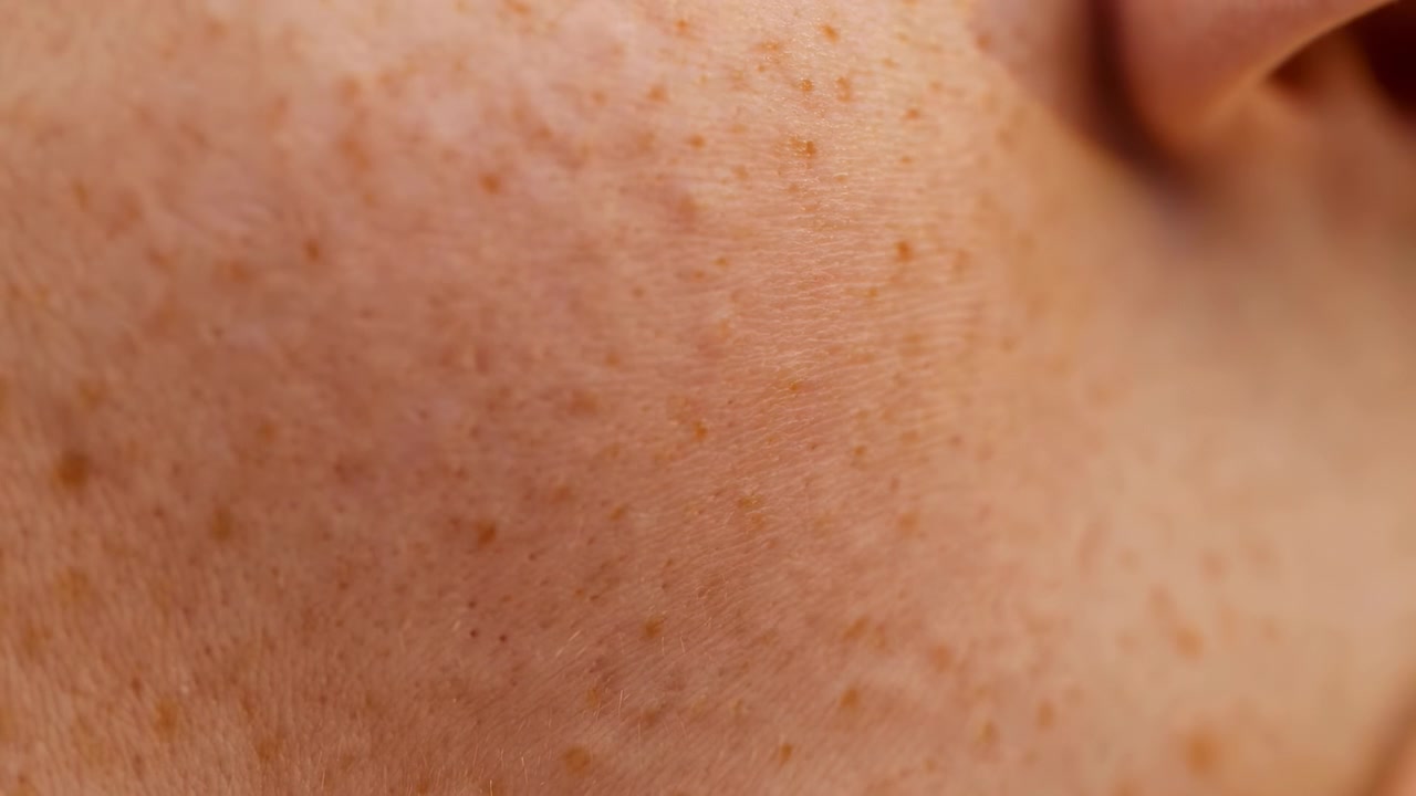 Vista macro captura la superficie de piel texturizada con movimiento suave e iluminación cambiante, revelando poros finos y variaciones de color cálidas en una composición cercana para temas de belleza, cuidado de la piel y textura