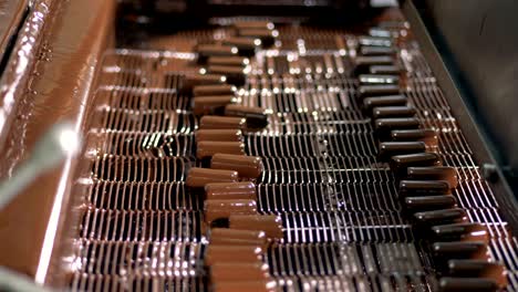 production of chocolates. candies covered by liquid chocolate on conveyor.