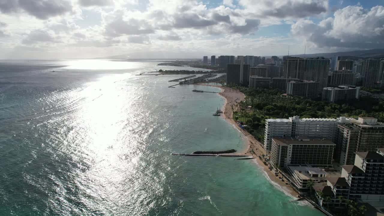 Splendida ripresa aerea con drone al tramonto in 4K mentre il drone scende su una destinazione di vacanza su un'isola tropicale, passando accanto a lussuosi hotel fronte mare proprio sulla sabbia.