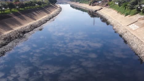 dark waters of tiete river flowing and reflecting the sky